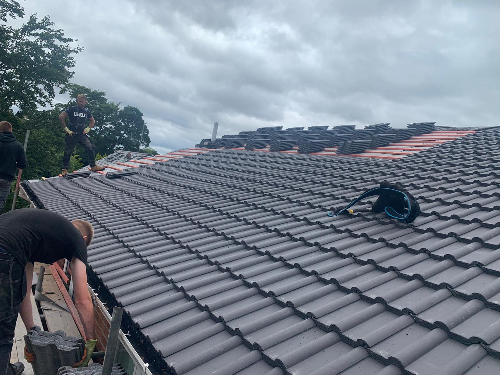 Roofers installing a new slate roof on a build in the North East